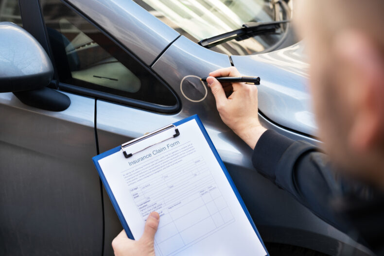 insurance company determining car accident fault by location after a car crash by inspecting car and taking notes