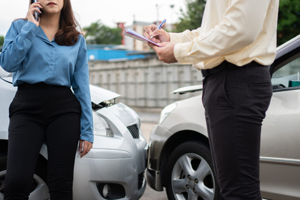 women Talk to Insurance Agent for examining damaged car. Concept of insurance and car traffic accidents.